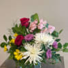 Mixed bouquet in a clear glass vase with red roses, white spider mums, and pink flowers