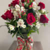 Bouquet of red roses and white alstroemeria in a glass vase with plaid ribbon