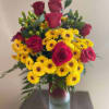 Bouquet of red roses and yellow daisies in a clear glass vase