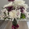 White and purple chrysanthemum bouquet in a glass vase with a ribbon