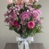 Pink roses and lilies arranged in a glass vase with a white ribbon
