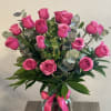 Pink roses in a glass vase with a pink ribbon