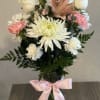 Bouquet of white and pink flowers in a glass vase with a pink ribbon