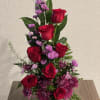Red roses and purple flowers in a clear glass vase