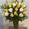 Yellow and white roses arranged in a tall glass vase