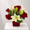 Red roses and white lilies arranged in a red square vase