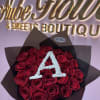 Bouquet of red roses wrapped in black paper with a white letter A