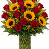 Bouquet of red roses and yellow sunflowers in a glass vase