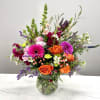 Mixed bouquet of orange and pink flowers in a glass vase