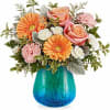 Pink roses and orange gerbera daisies in a blue glass vase