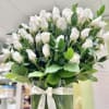 Arrangement of white rosebuds in a clear square vase with white ribbon