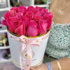 Round box filled with bright pink roses tied with a pink ribbon