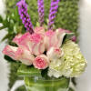Low arrangement of pink roses, white hydrangea and tall purple spikes in a round glass bowl vase
