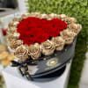 Round black hatbox of red and gold roses with red blooms shaped into a heart.