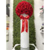 Tall white cylinder vase topped with a dome of red roses and a red bow