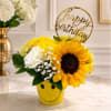 Sunflower and white flower arrangement in a yellow smiley-face pot with a birthday topper