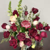 Bouquet of deep red roses with a pink protea and small white filler flowers