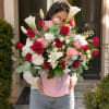 Large bouquet of red, pink, and white flowers in a pink hatbox