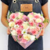 Heart-shaped box filled with pink and cream roses and other blooms
