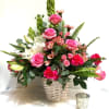 Pink roses and lilies arranged in a woven basket with greenery