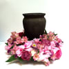 Pink floral arrangement around a dark urn-shaped vase