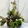 Mixed tropical plant arrangement in a low glass bowl with tall branches