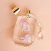 Clear perfume bottle with floral print and gold cap on a pink background
