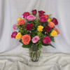 Mixed bouquet of bright roses in pink, orange, yellow, and red arranged in a clear glass vase