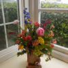 Colorful mixed flower arrangement in a wooden container on a windowsill