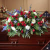 Red, white, and blue floral spray arranged on a wooden casket