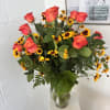 Bouquet of coral roses and yellow daisies in a clear glass vase