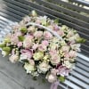 Handheld bouquet of pale pink and white flowers with a braided handle