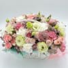 Pastel bouquet of pink, white, and green flowers in a white basket