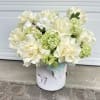 Cream roses and green hydrangeas in a white container