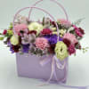 Lavender gift bag filled with pink, purple, and white flowers