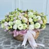 Basket of pale pink and white flowers with a ribbon bow
