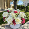 White roses and hot pink flowers arranged in a round gray vase