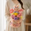 Woman holding a pastel bouquet with a plush bunny and roses
