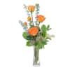 Orange roses in a clear glass vase with eucalyptus
