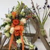 Orange and white floral wreath with roses and lilies on a wooden frame