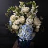 White roses and blue hydrangeas in a dark blue vase