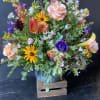 Mixed bouquet with peach roses, purple blooms, and yellow daisies in a vase