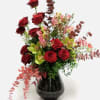 Red roses and pink flowers in a black vase