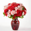 Red roses and pink carnations in a red glass vase