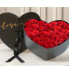 Heart-shaped box filled with red roses and a black ribbon