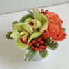 Compact bouquet with orange roses, green orchids, and red berries in a white vase