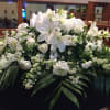 Large white floral arrangement with lilies and roses on a table