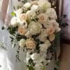 Bride holding a cascading bouquet of white and blush flowers