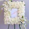 White floral wreath on an easel with roses and lilies