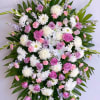 Large standing spray of pink and white flowers with palm leaves